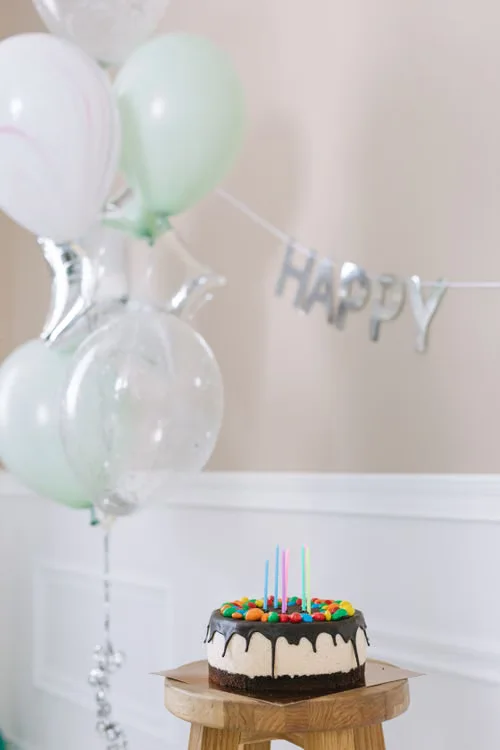 Birthday inspiration: pastel balloons and a candle-topped cake. Stock photograph.